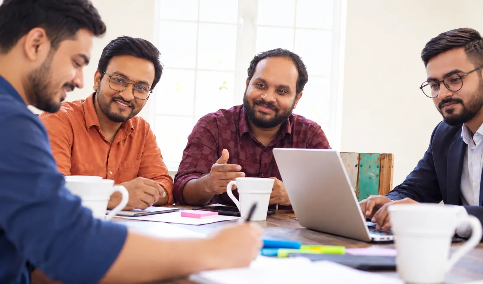 weDevs teammates in discussion around a meeting table